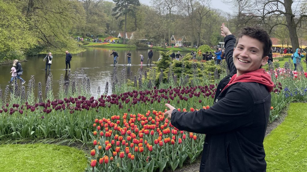Honors College student gestures to a garden of tulips in the Netherlands
