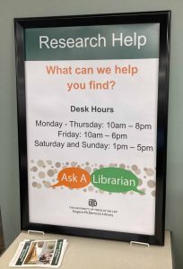 Sign with desk hours at library